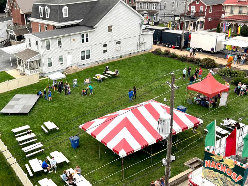 Aerial view of the Town Centre Green with the empty Main Street Stage on the left and various tents and concessions around the other edges.